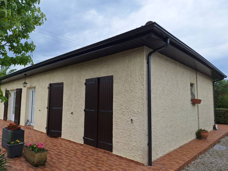 Habillage des avancées de toit avec gouttières corniche, bandeaux et sous-faces en aluminium noir pour un contraste net et élégant.